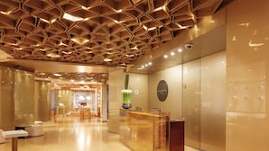 A modern hotel lobby with a geometric ceiling design, a reception desk, and a seating area. - BOG Hotel  (Bogotá)