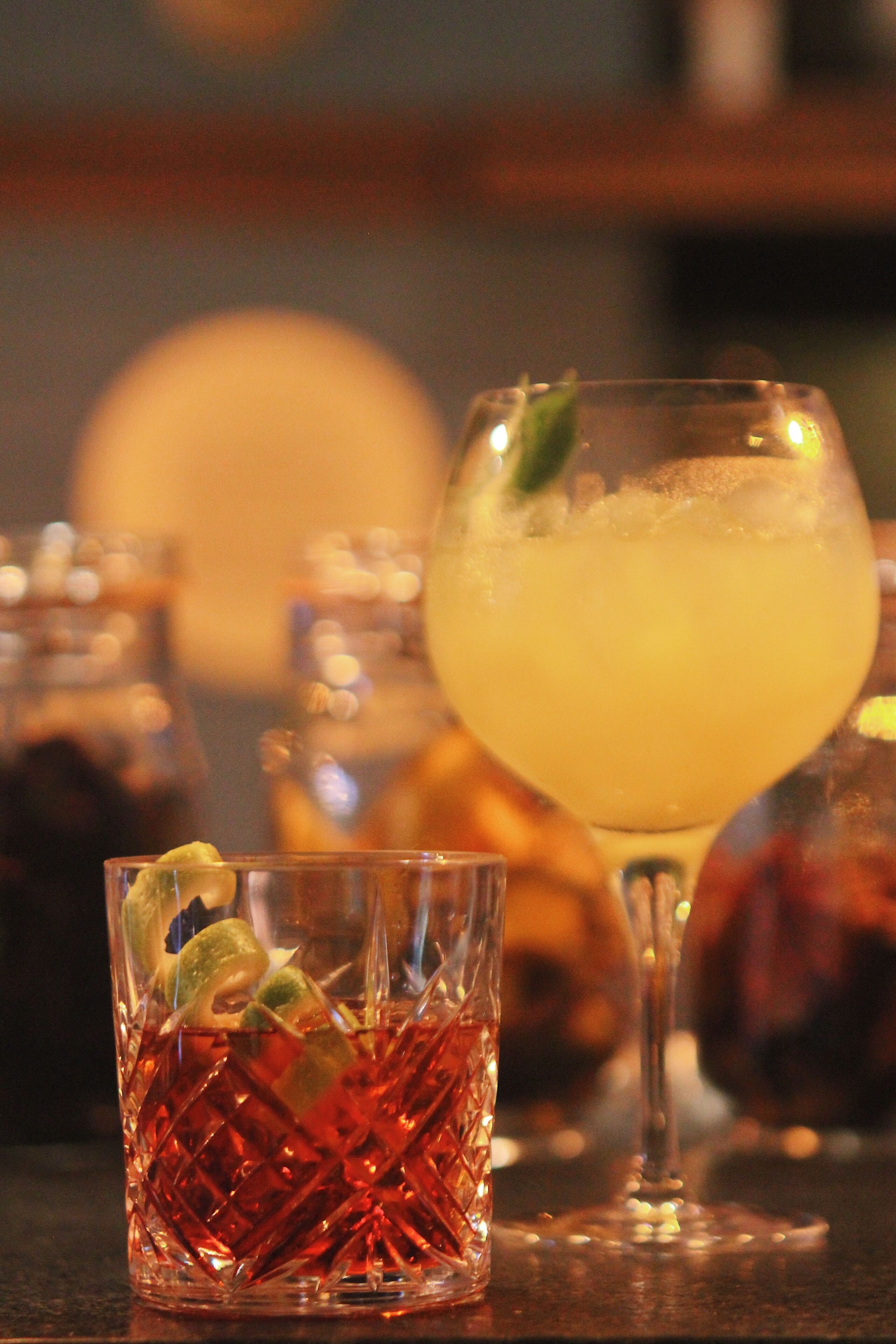 A bar setting with a variety of glasses containing different beverages, some with garnishes.