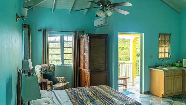 Un dormitorio con cama, una silla, armario, ventilador de techo y vistas al exterior.