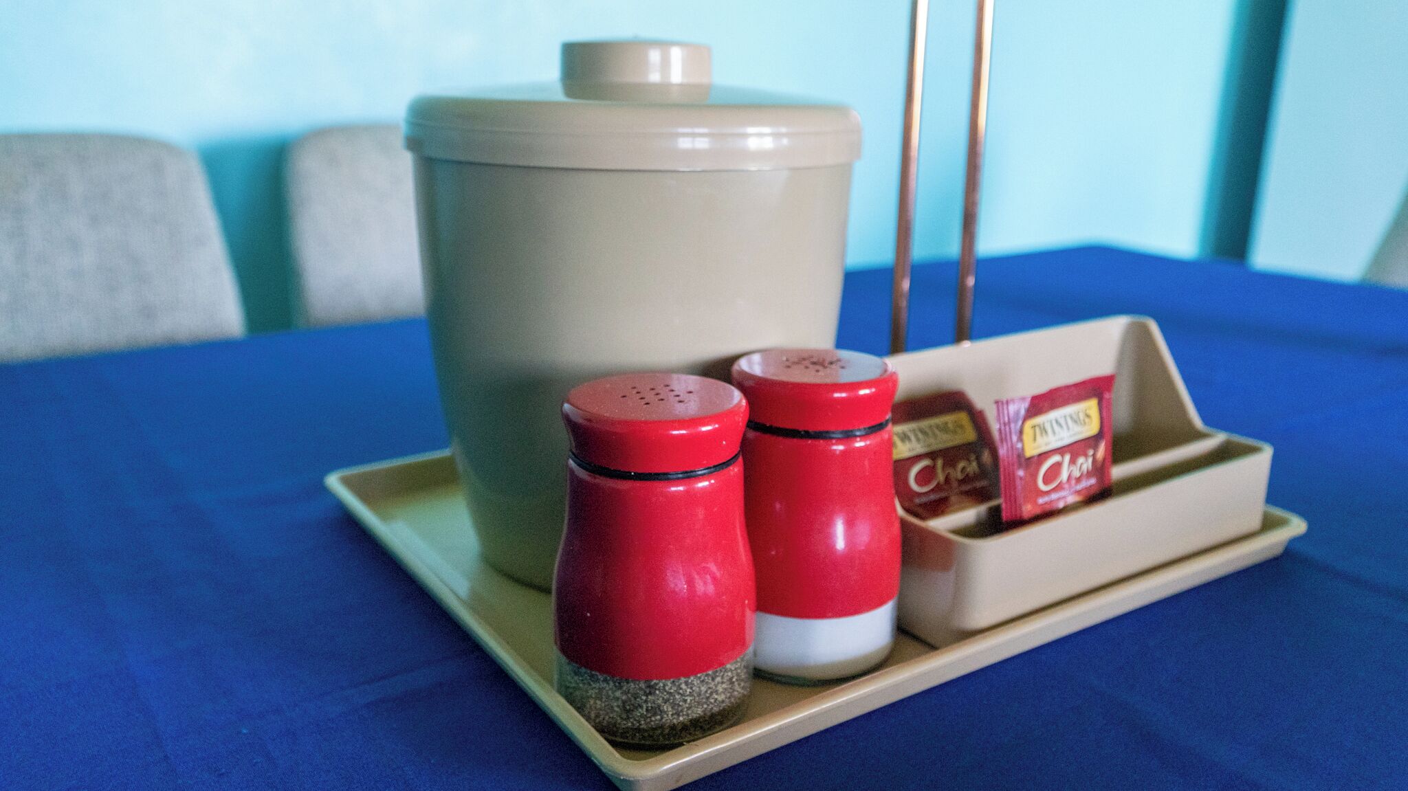 Zona cuina amb un recipient beix gran, dos salaboters vermells i una safata amb bosses de te Chai Twinings.