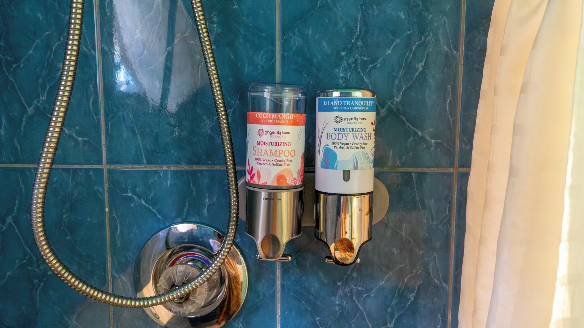 Une salle de bain équipée d’une douche, d’un pommeau de douche et de deux bouteilles de shampoing.