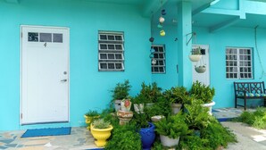 A turquoise house with a white door, multiple windows, and various potted plants. - LambLion Holiday Apartments (Freemans Village)