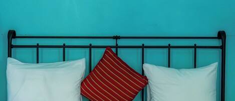 A bed with a metal frame, two white pillows, and a red striped pillow.