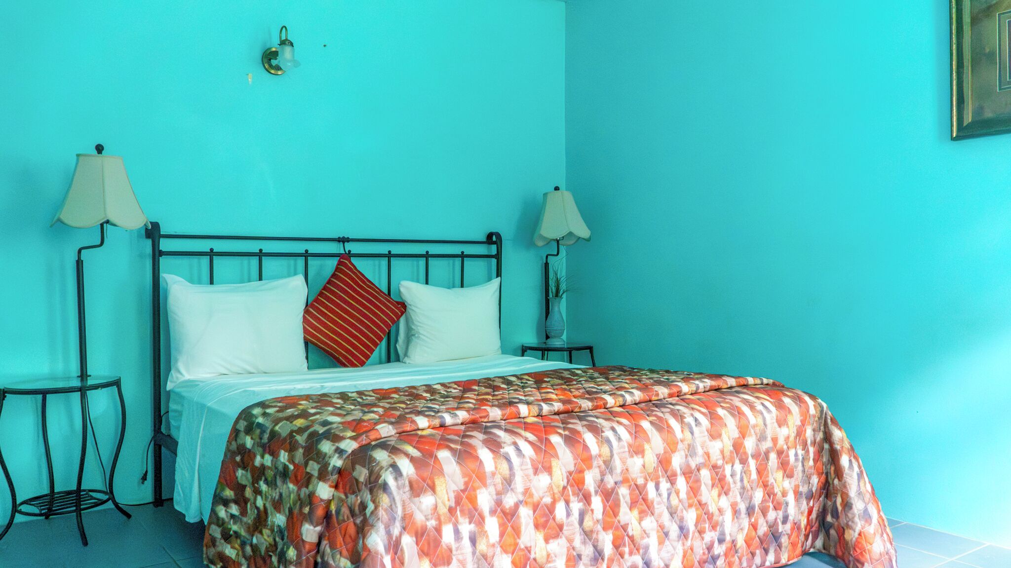 A room with a bed, two bedside tables, and a wall-mounted lamp.