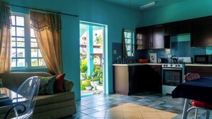 A kitchen with a stove, microwave, and sink. There is a dining table with chairs and a sofa with cushions. - LambLion Holiday Apartments (Freemans Village)