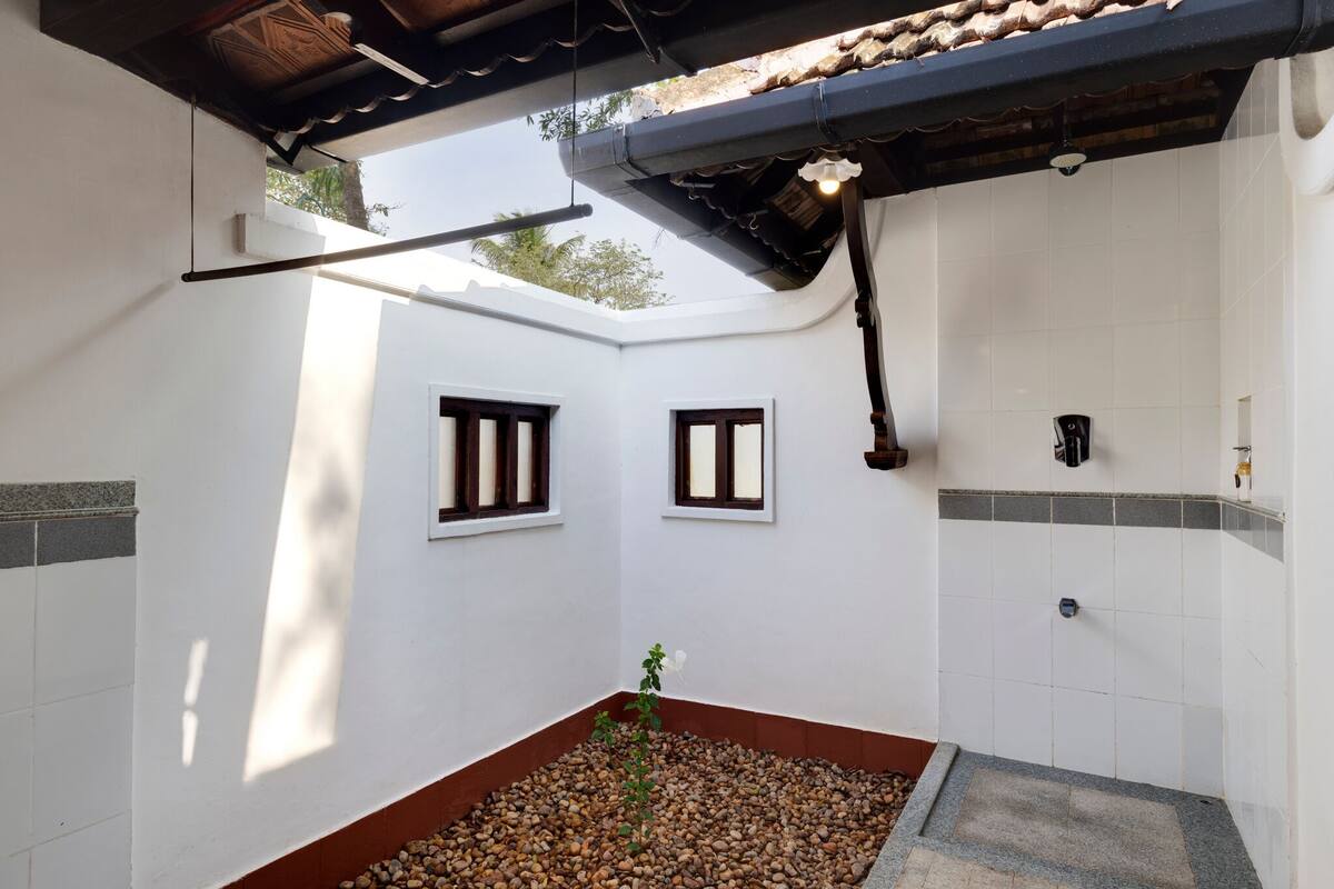 Une pièce aux murs blancs, avec une douche carrelée et une petite fenêtre.