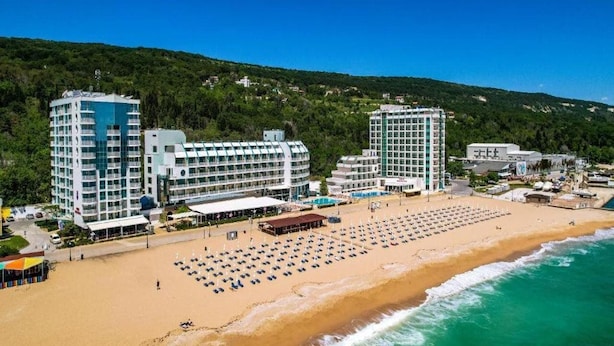 A beachfront hotel with multiple high-rise buildings, a sandy beach with sun loungers, and a view of the ocean. - Berlin Golden Beach Hotel (Golden Sands)