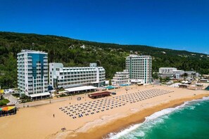 A beachfront hotel with multiple high-rise buildings, a sandy beach with sun loungers, and a view of the ocean. - Berlin Golden Beach Hotel (Golden Sands)