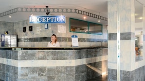 A reception area with a marble counter, a sign reading "RECEPTION", and a woman standing behind it. - Berlin Golden Beach Hotel (Golden Sands)
