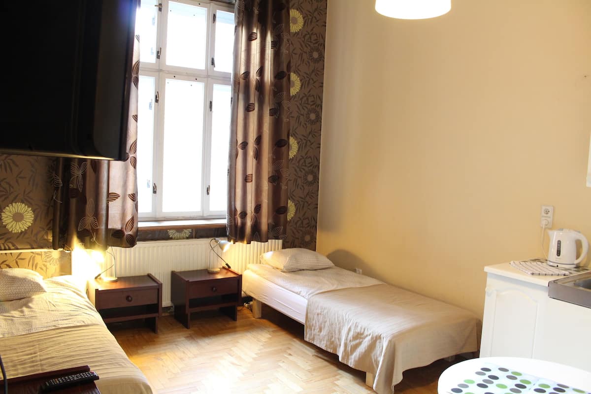 A room with two beds, a small table, a kettle, and a radiator.