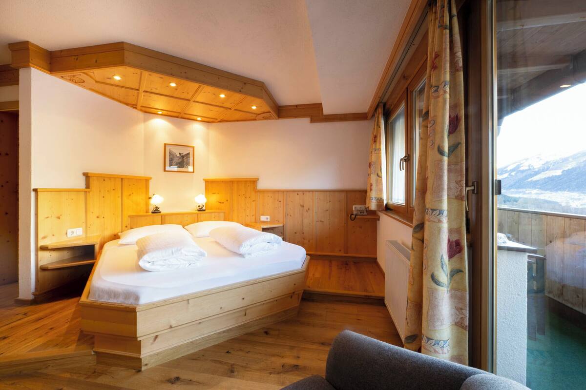 Un dormitorio de madera con cama, mesitas de noche y ventana con vistas.
