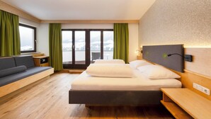Habitación de hotel moderna con cama, zona de estar y vistas a un paisaje nevado.