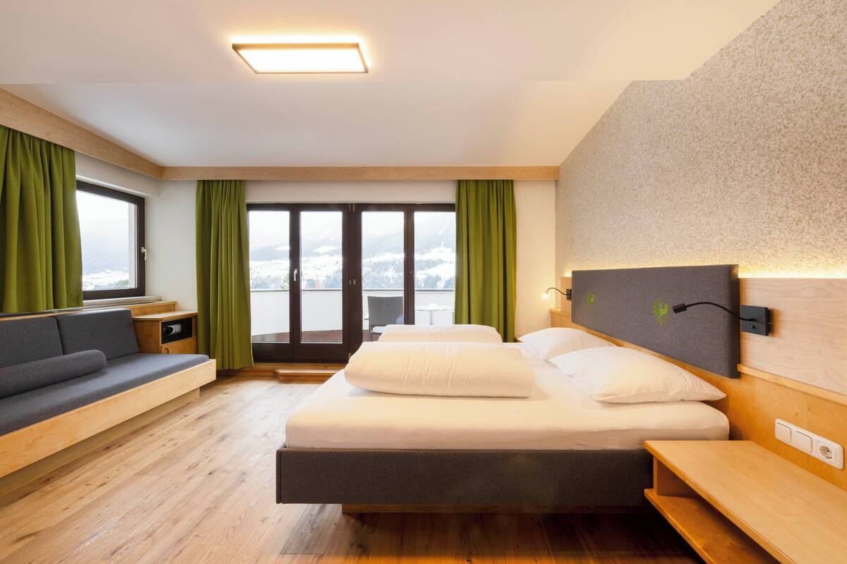 Habitación de hotel moderna con cama, zona de estar y vistas a un paisaje nevado.
