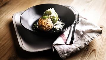 Un plato con comida sobre una superficie negra, un tenedor y una servilleta de tela sobre una mesa de madera.