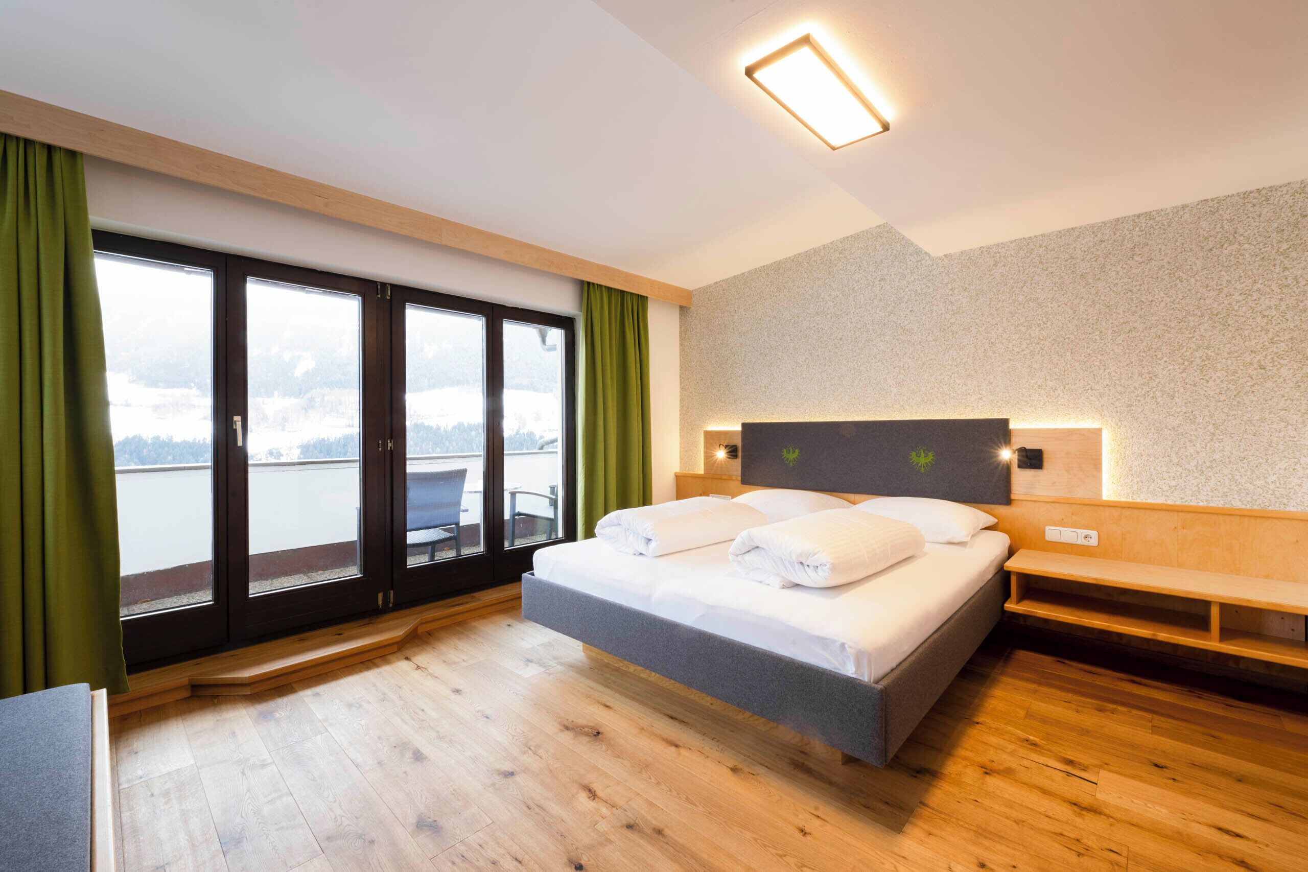 Camera d'albergo con un letto, una panca, vista su uno specchio d'acqua e sullo skyline della città.