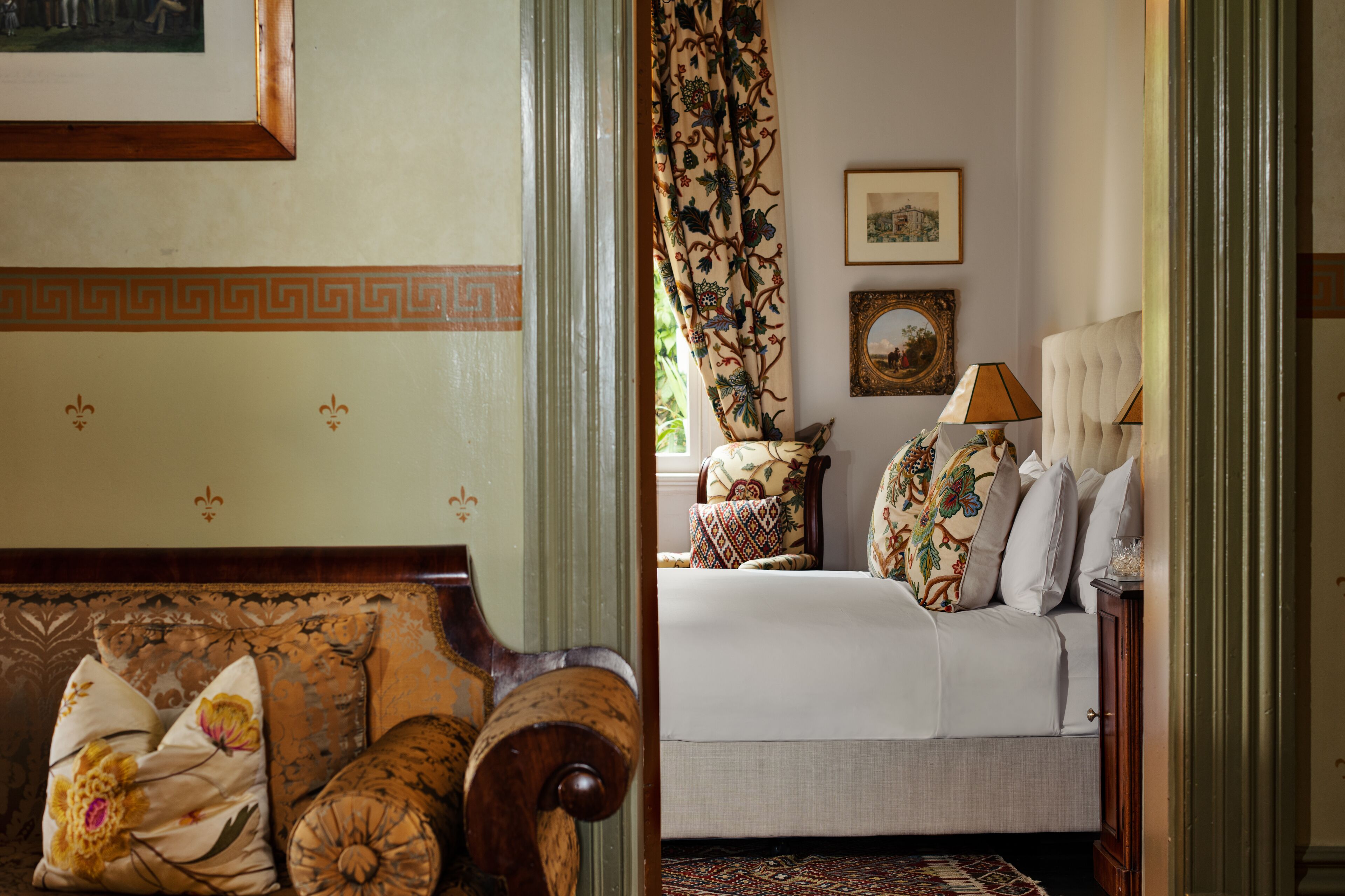 Een kamer met een bed, een stoel, een lamp en een ingelijst beeld aan de muur.