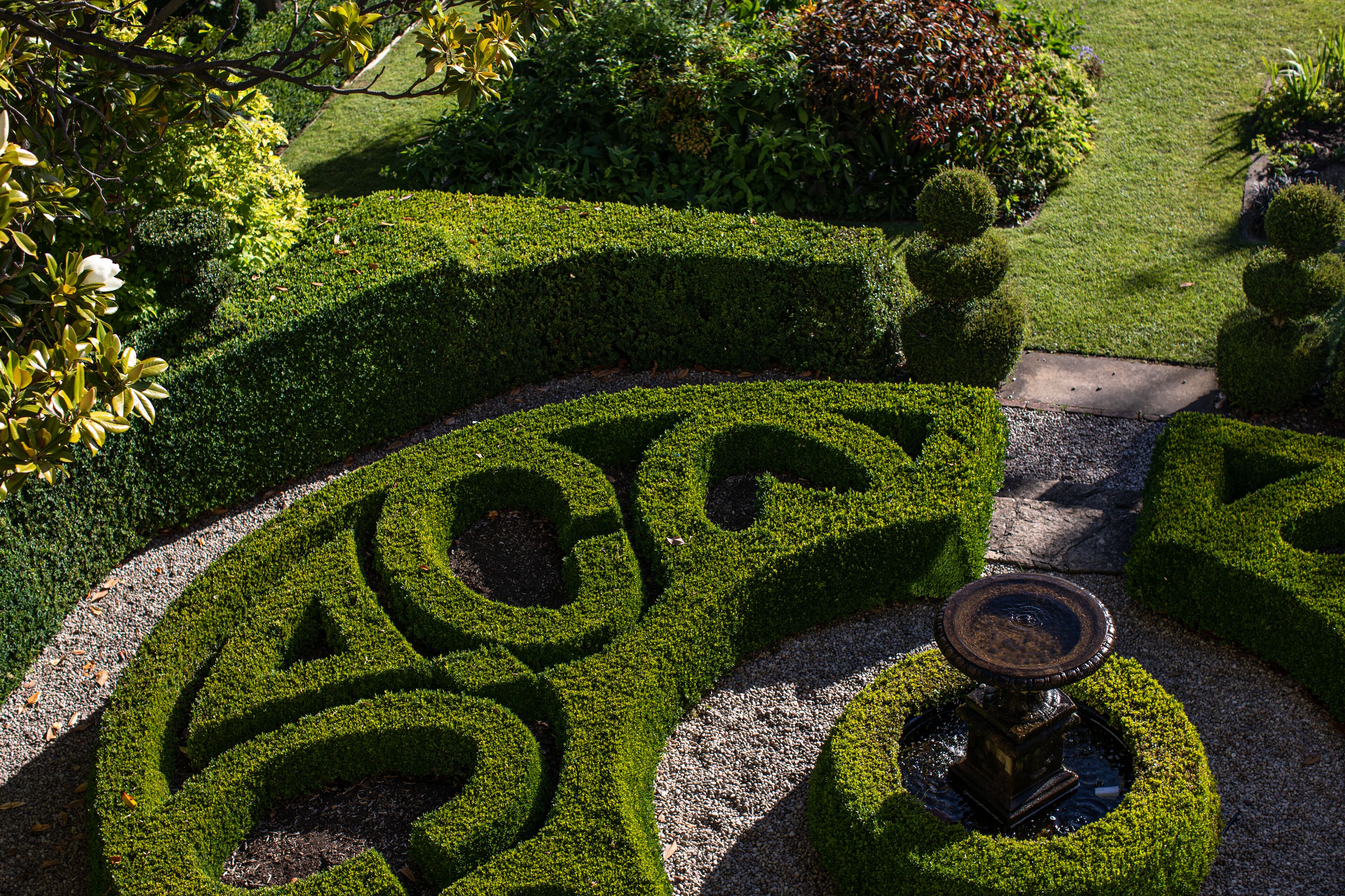 A meticulously landscaped garden with geometric hedge designs and a central fountain.