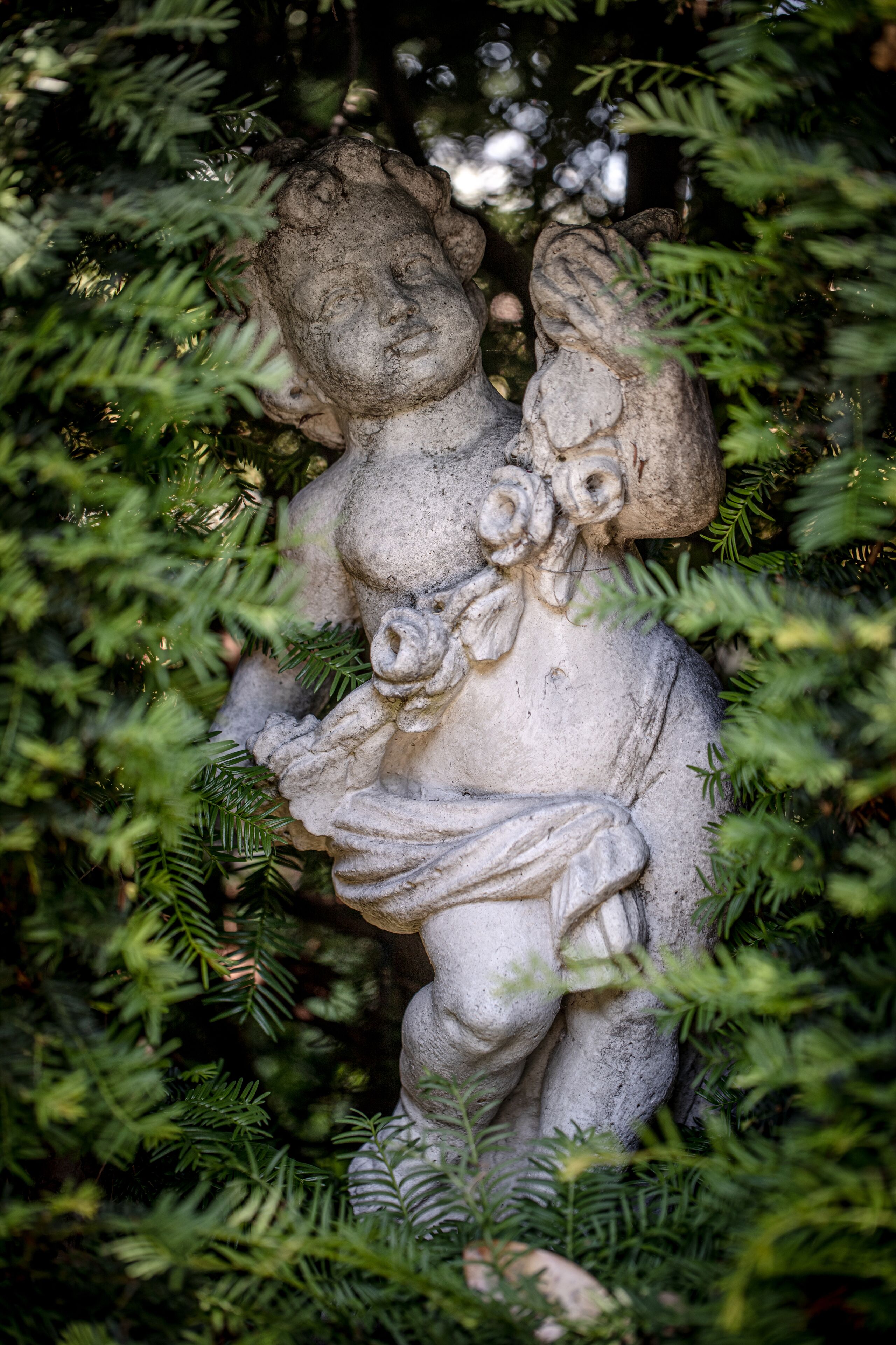 Una estatua de piedra parcialmente cubierta por follaje verde.