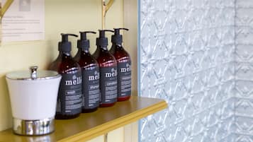Et badeværelse med en hylde med Mielle shampoo og conditioner, en hvid vask og en tissueskasse.