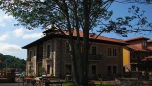 A courtyard with outdoor seating, stone buildings, and a tree. - Hotel & Spa María Manuela (Onis)