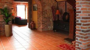 A spacious living area with a brick fireplace, a staircase, and a large window allowing natural light. - Hotel & Spa María Manuela (Onis)