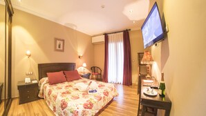 A hotel room with a bed, bedside tables, a TV, a desk with a chair, and a dining table set for two. - Hotel & Spa María Manuela (Onis)