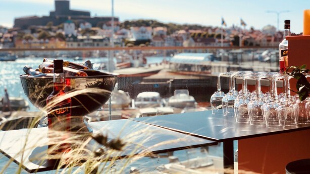 A bar with a view of a harbor, including boats and a distant building. - Marstrands Havshotell (Marstrand)