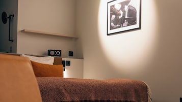 Habitación de hotel moderna con cama, una silla, un escritorio y un cuadro en la pared.