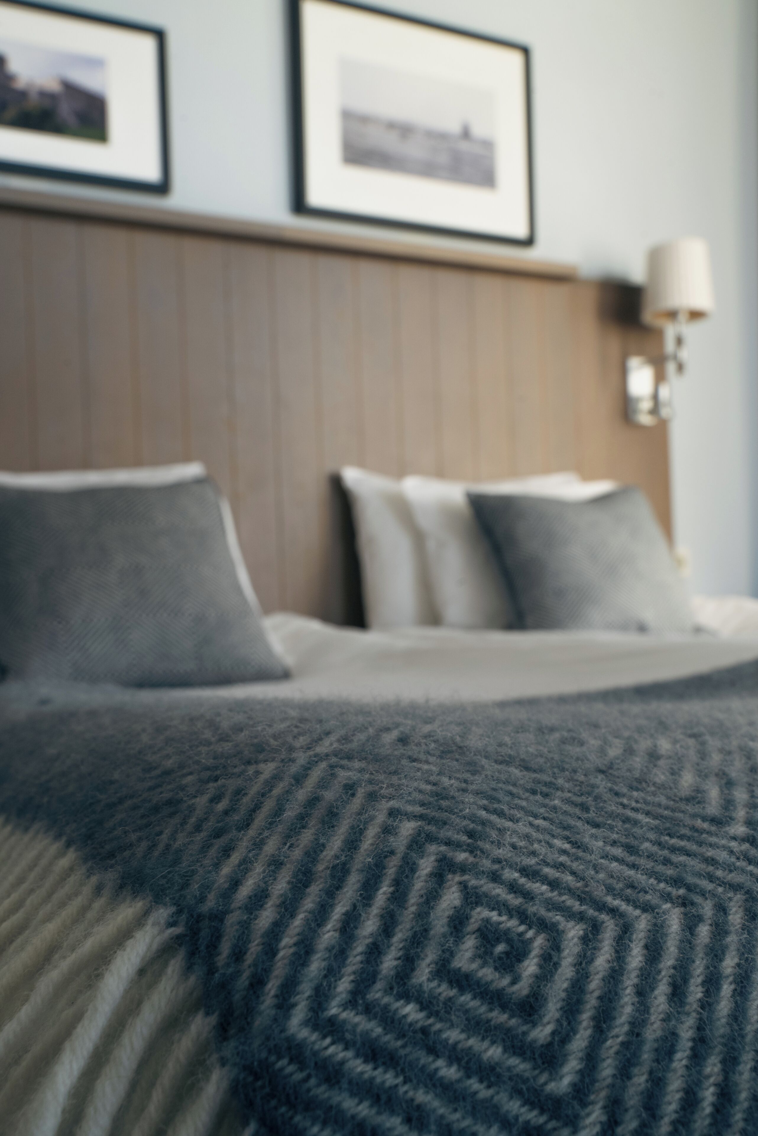 Ein Hotelzimmer mit Bett, Kissen, einer Lampe und gerahmten Bildern an der Wand.