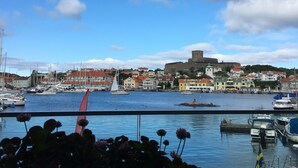 A harbor with boats, a sailboat, and a castle-like structure on a hill. - Marstrands Havshotell (Marstrand)