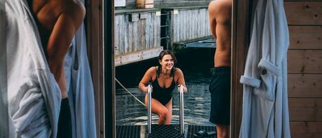 A person in a black swimsuit on a step ladder outside a wooden building.