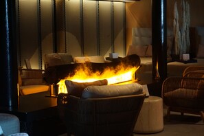 A room with a sofa, a coffee table, and a fireplace with a fire. - Marstrands Havshotell (Marstrand)