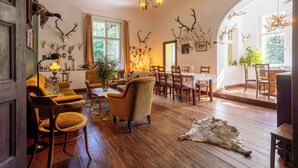 Ein Zimmer mit Holzboden, einem Essbereich mit Tisch und Stühlen sowie einem großen Fenster mit Vorhängen.