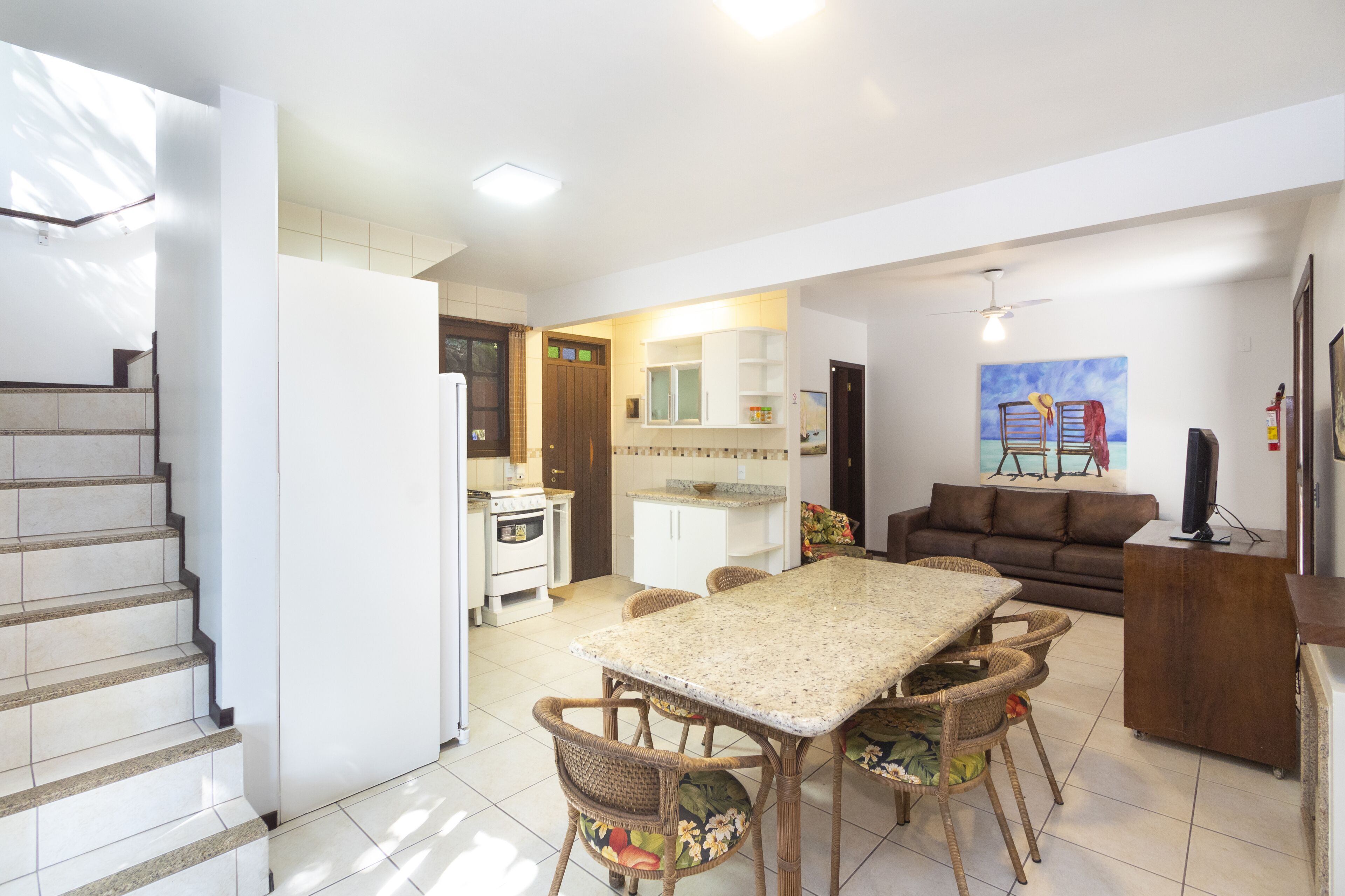 A spacious living area with a dining table and chairs, a sofa, and a television.