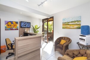 Un área de recepción con un escritorio de madera, un televisor y obras de arte en las paredes.