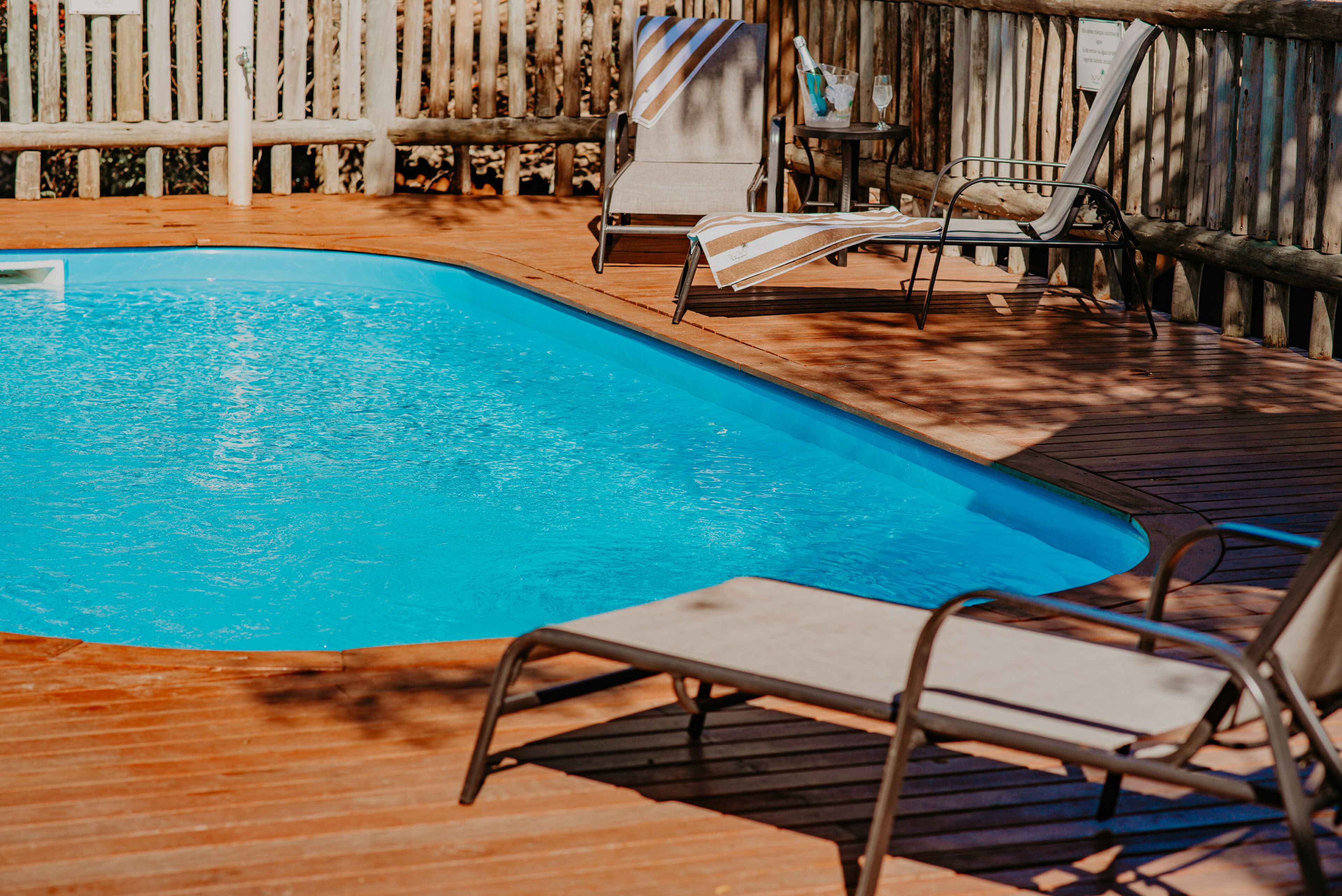 A swimming pool with lounge chairs and a wooden deck.
