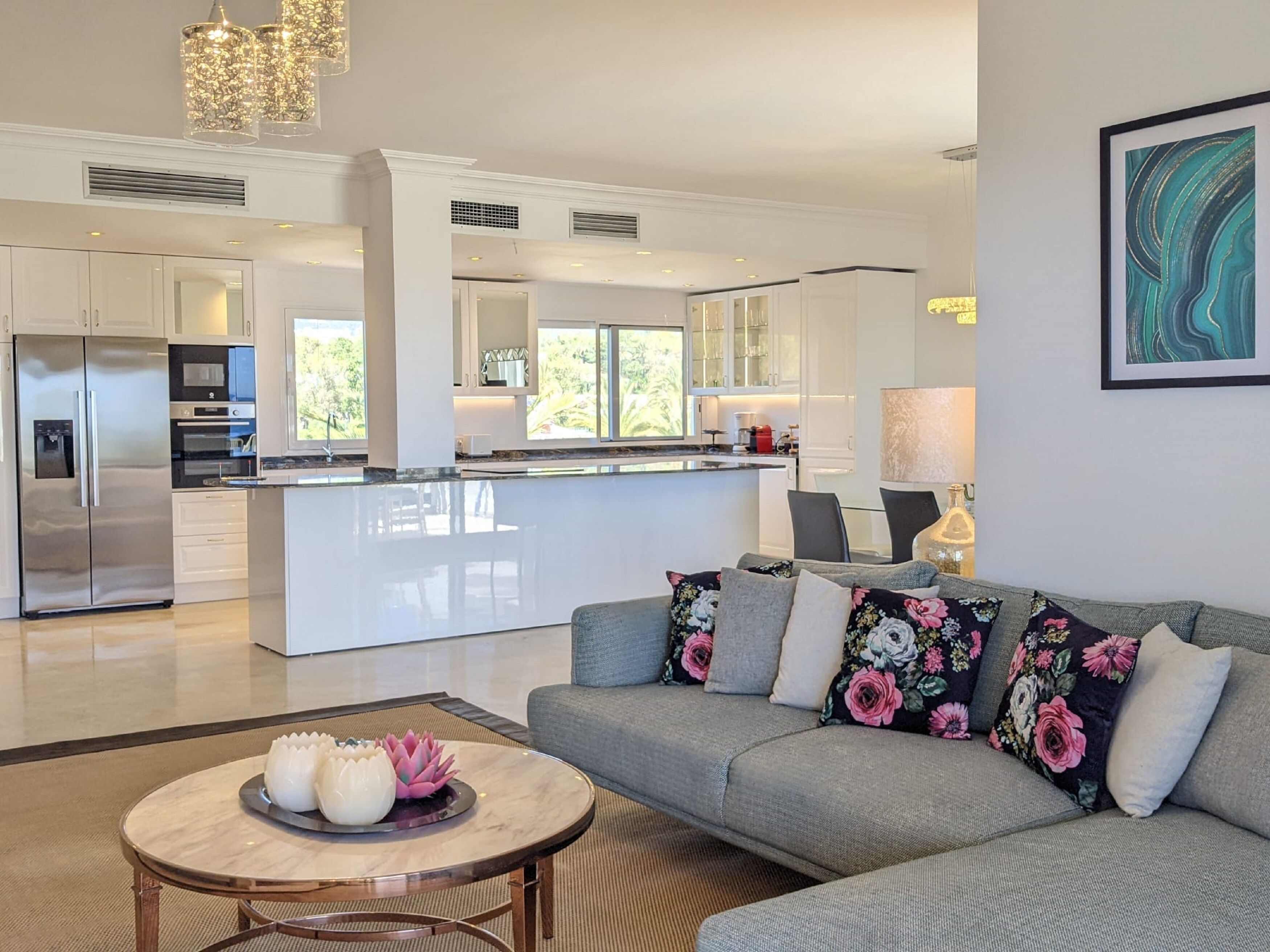 A modern kitchen with a central island, stainless steel appliances, and a dining area with a sofa and coffee table.