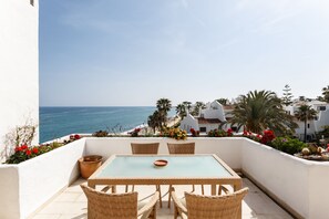 A terrace with a table and chairs, overlooking a beach and ocean. - Coral Beach Aparthotel (Marbella)