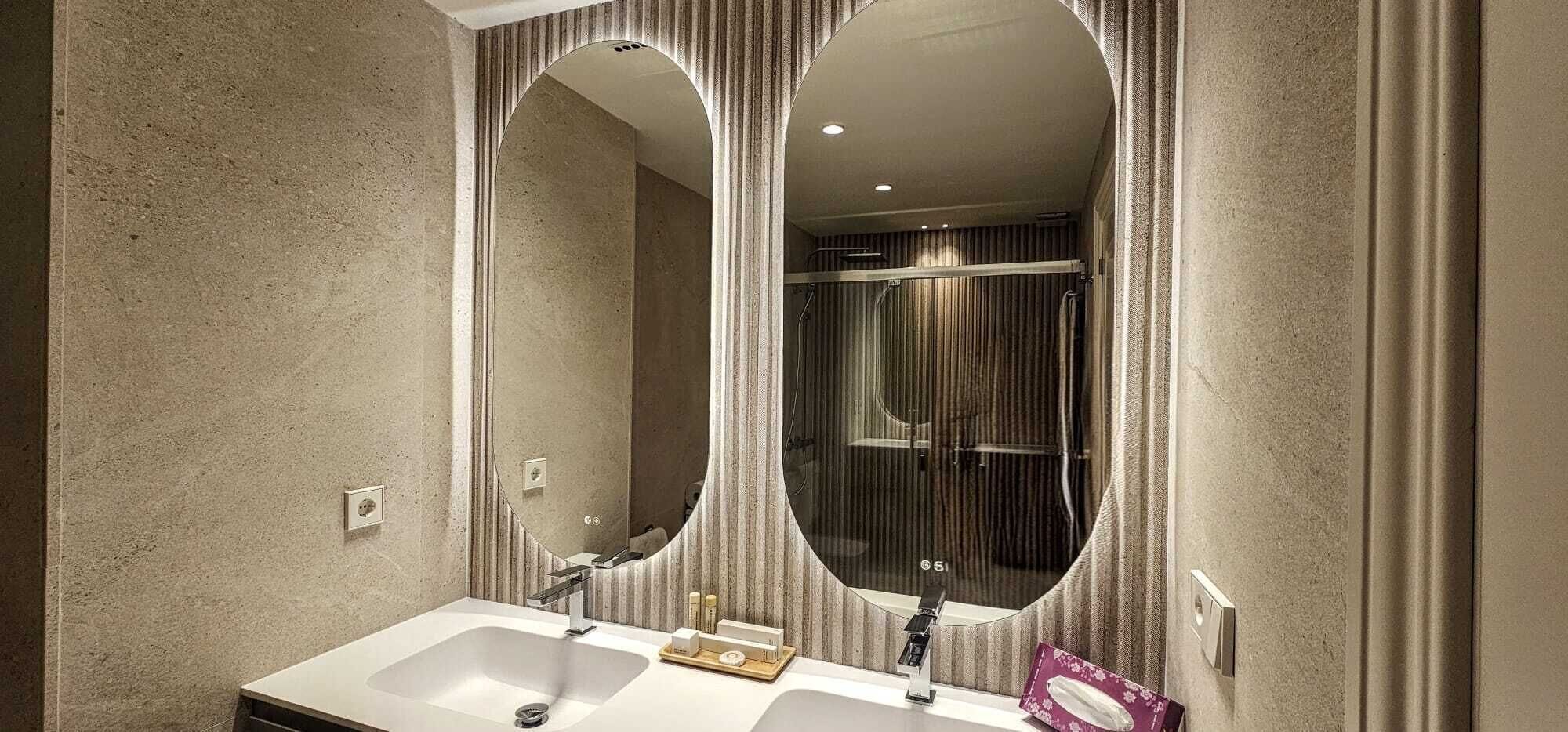 A bathroom with two sinks, a mirror, and a shower area.