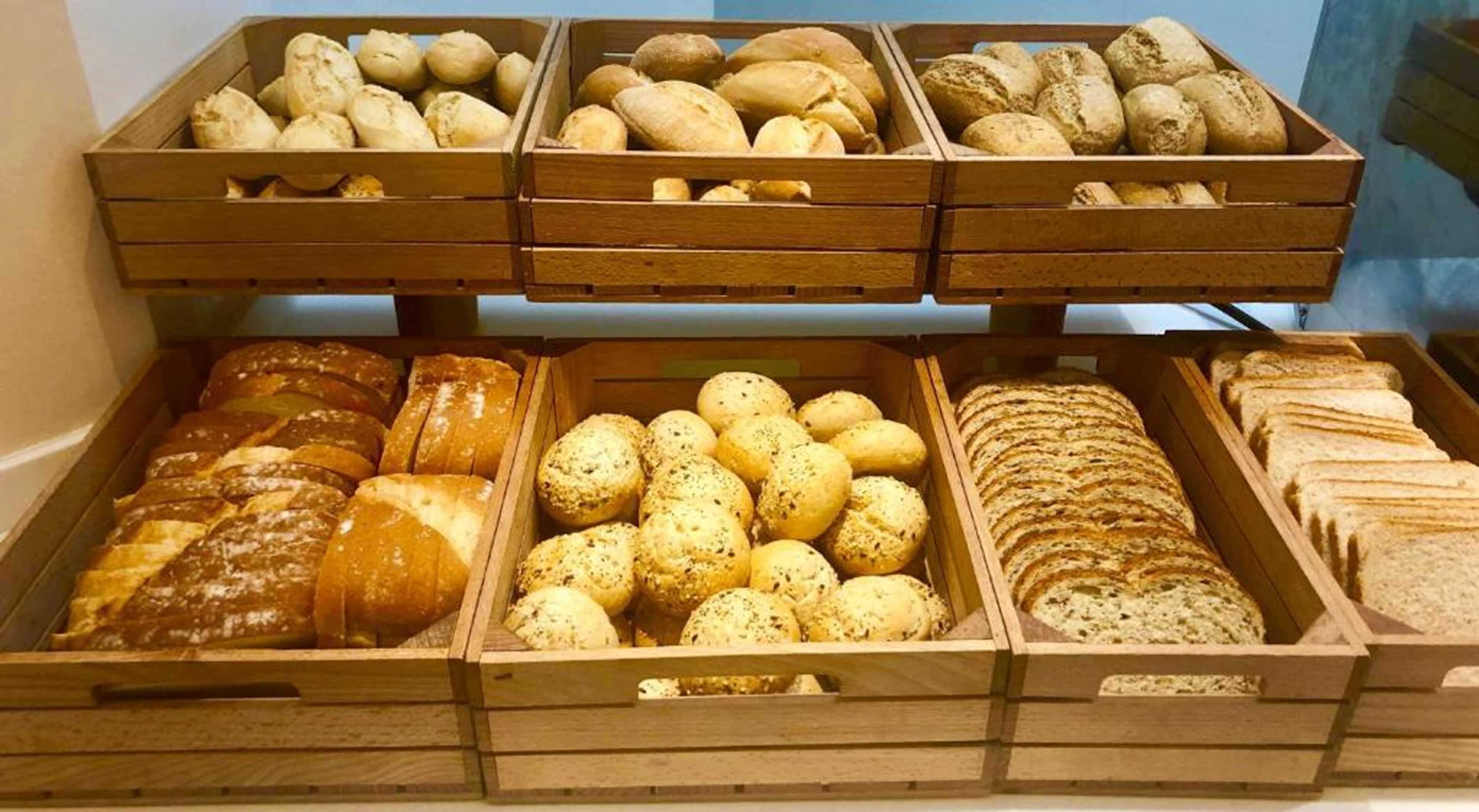 Mostrador de panadería con diferentes tipos de pan y pasteles en cajas de madera.