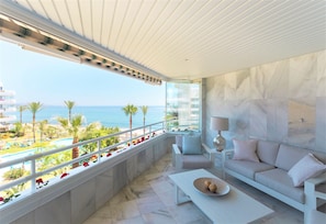 A balcony with a view of the sea, a sofa, a table, and a lamp. - Coral Beach Aparthotel (Marbella)