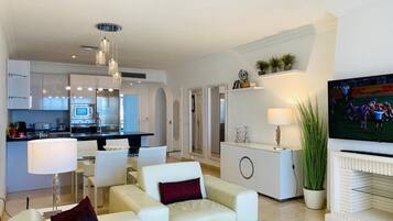 A modern living room with a sofa, a glass coffee table, and a flat-screen TV.