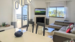 Una sala de estar moderna con televisión, sofá y comedor.