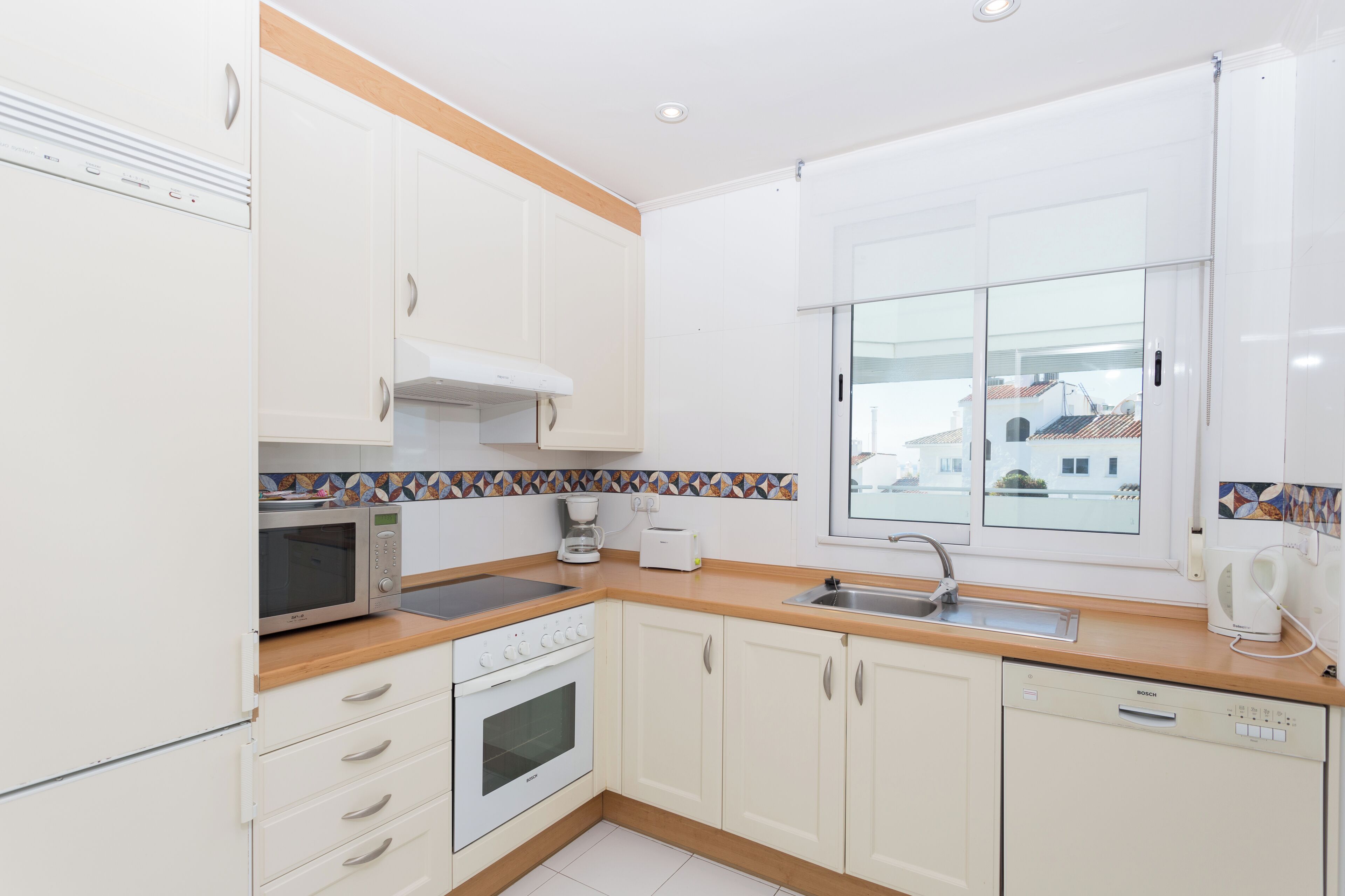 A modern kitchen with white cabinets, a microwave, a coffee maker, and a dishwasher.