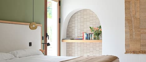 Ein Schlafzimmer mit einem Bett, einer Pendelleuchte, einem Bücherregal und einem Fenster.