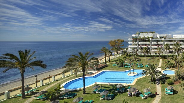 Un complejo turístico con piscina, playa y vista al océano.