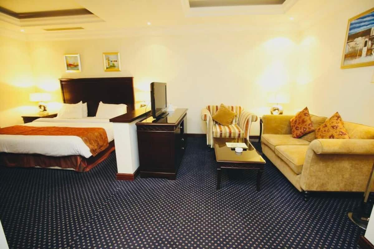 Une chambre d’hôtel avec un lit, un canapé, une petite table et un téléviseur.