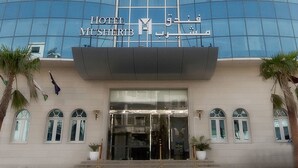 The exterior of the Hotel MushiRib with a modern glass facade, a prominent entrance with a canopy, and symmetrical window design. - Musherib Hotel (Doha)