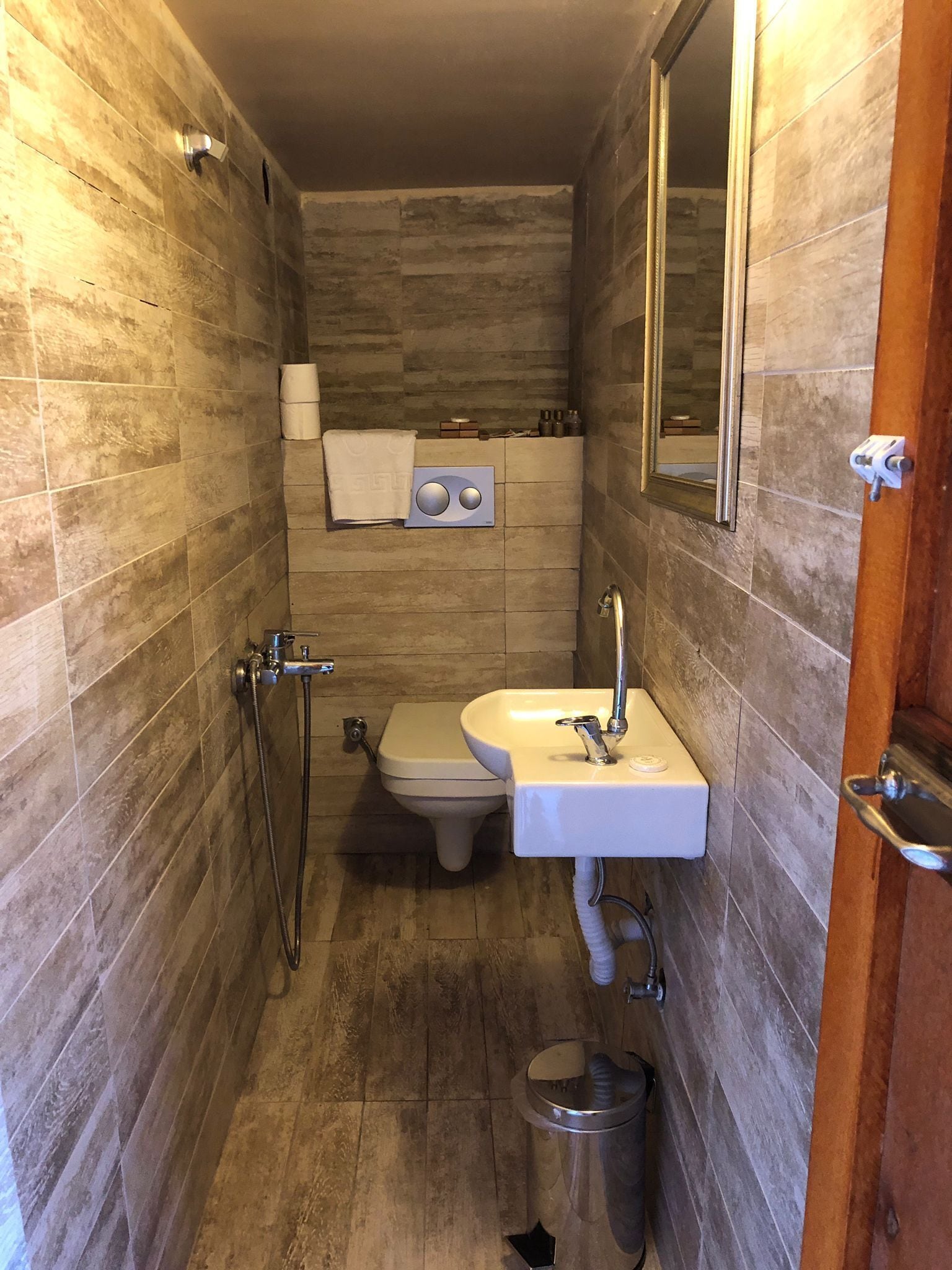 A compact bathroom with a toilet, sink, and shower.