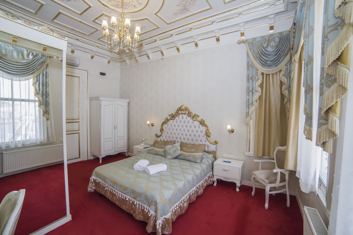 A spacious bedroom with a large bed, a sitting area, and a wardrobe.